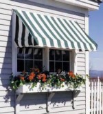 Greeen and white stripes awnings installed over a window with a flower box under