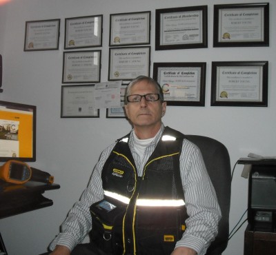 Robert Young dans son bureau de Montréal où sont visibles les certificats obtenus pour son service d'inspection de maisons
