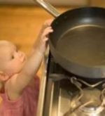 Little girl reaching for a frying pan on a stove