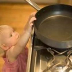 Little girl reaching for a frying pan on a stove